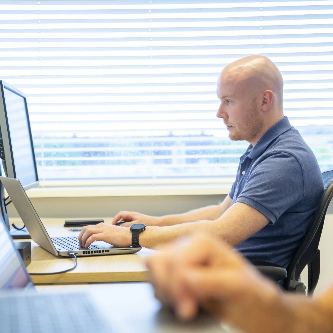 isah-lösung-project-management-mitarbeiterim-hintergrund-am-schreibtisch-bureau-achtergrond